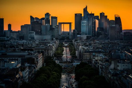 Cette photo saisit une vue saisissante d'une ville au coucher du soleil, mettant en valeur une silhouette dominée par des bâtiments imposants. La Défense. 