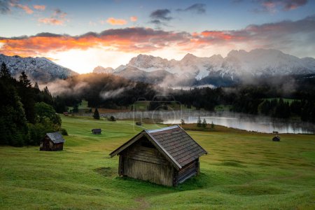 A scenic view of log cabins against a Geroldsee lake and the Karwendel mountains, Bavaria. High quality photo