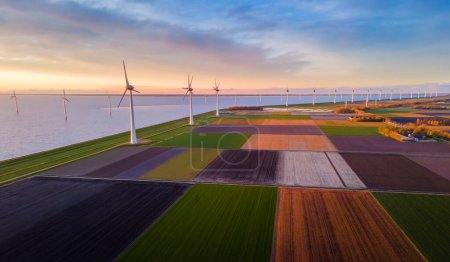 Una perspectiva aérea captura una serie de turbinas eólicas situadas en un campo bajo un cielo nublado, creando un paisaje sostenible en una ecorregión