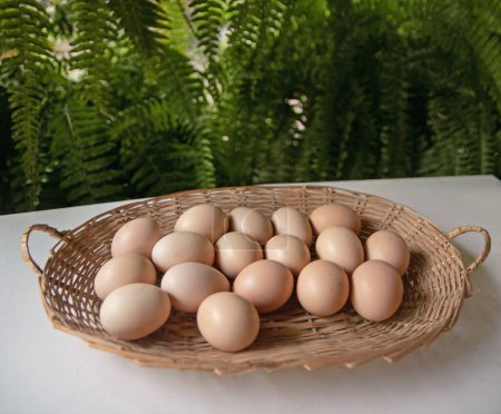 Photo for Straw basket with many eggs on white table - Royalty Free Image
