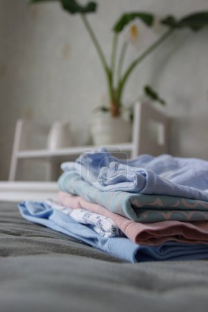 Téléchargez les photos : Vêtements de couleur propre sur le lit dans une chambre, fond doux focus - en image libre de droit