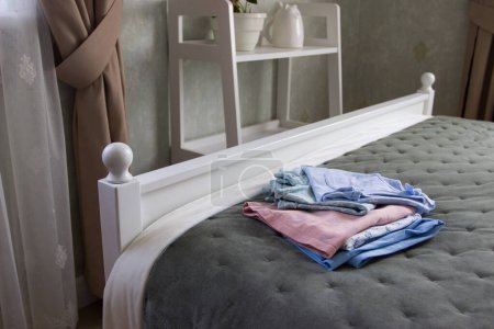 Téléchargez les photos : Vêtements de couleur propre sur le lit dans une chambre, fond doux focus - en image libre de droit