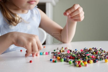 Photo for Process of making a bracelet from a thread and colored beads, concept of hobby or leisure - Royalty Free Image
