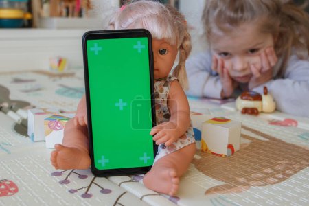 Photo for Smartphone with a green screen. Concept of education online. Little kid with toys in the playroom - Royalty Free Image