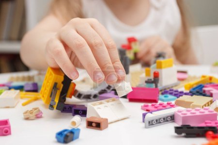 Téléchargez les photos : Enfant construit avec des briques de constructeur, joue avec des jouets, fond de mise au point douce - en image libre de droit