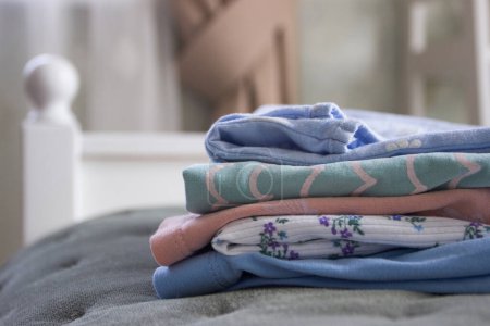 Photo for Clean colored clothes on the bed in a bedroom, soft focus background - Royalty Free Image