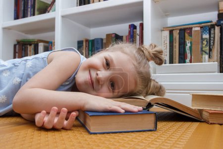 Little cute girl sleeping with books in the front of bookshelf. Concept of education, soft focus background