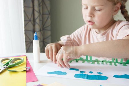 Photo for Cute child creating an applique with colored paper and glue. Concept of hobby and education - Royalty Free Image