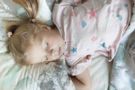Téléchargez les photos : Petite fille mignonne allongée dans le lit. Concept d'éveil le matin - en image libre de droit