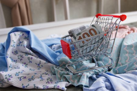 Photo for Shopping cart with American dollars and different clothes. Concept of traveling or shopping - Royalty Free Image