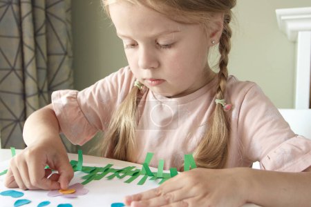 Foto de Lindo niño creando un apliques con papel y pegamento de colores. Concepto de hobby y educación - Imagen libre de derechos