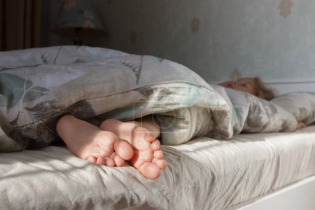 Foto de Pies debajo de una manta ligera en la cama. Concepto de vida saludable - Imagen libre de derechos