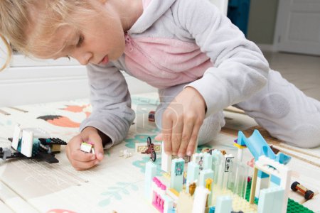 Téléchargez les photos : Enfant construit avec des briques de constructeur, joue avec des jouets, fond de mise au point douce - en image libre de droit