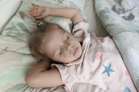 Foto de Niña linda acostada en la cama. Concepto de despertar por la mañana, fondo de enfoque suave - Imagen libre de derechos