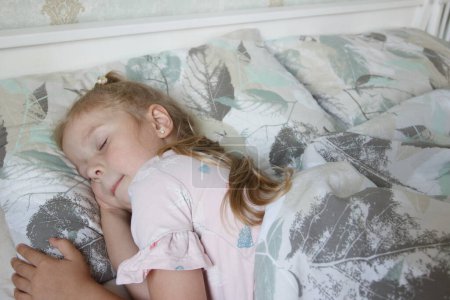 Téléchargez les photos : Petite fille mignonne allongée dans le lit. Concept d'éveil le matin, fond de mise au point douce - en image libre de droit