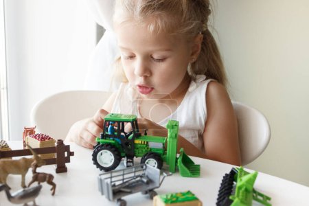 Foto de Lindo niño juega con juguetes de equipo de granja. Concepto de empresa o agricultura, fondo borroso - Imagen libre de derechos