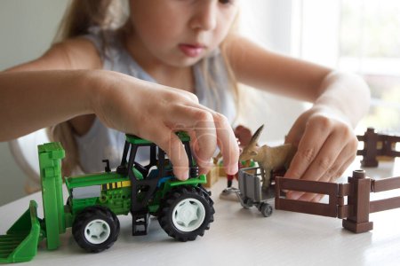 Foto de Lindo niño juega con juguetes de equipo de granja. Concepto de empresa o agricultura, fondo borroso - Imagen libre de derechos
