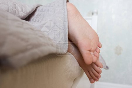 Photo for Feet under a light blanket on the bed, soft focus background. Concept of healthy life - Royalty Free Image