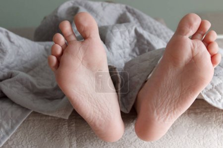 Foto de Pies debajo de una manta ligera en la cama, fondo de enfoque suave. Concepto de vida saludable - Imagen libre de derechos