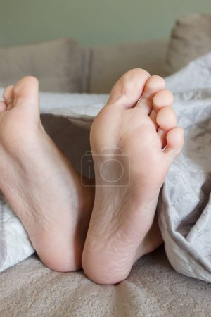 Foto de Pies debajo de una manta ligera en la cama, fondo de enfoque suave. Concepto de vida saludable - Imagen libre de derechos