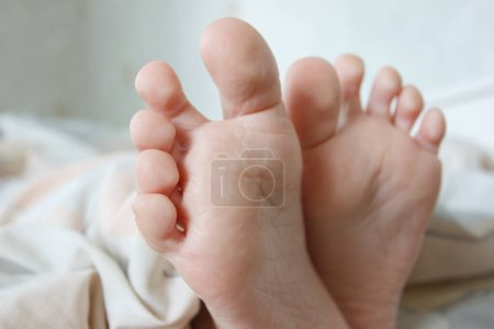 Photo for Feet under a light blanket on the bed, soft focus background. Concept of healthy life - Royalty Free Image