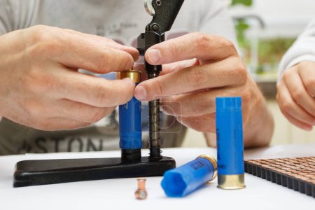 Téléchargez les photos : Un homme faire la réparation du boîtier en plastique pour la fabrication d'une cartouche pour le tir ou la chasse - en image libre de droit