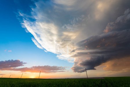 Foto de Nubes de tormenta se desvanecen iluminan impresionantes colores en el sol poniente sobre campos verdes - Imagen libre de derechos
