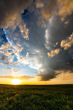 Coucher le soleil allume un nuage de tempête spectaculaire sur de beaux champs