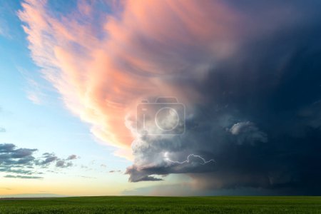 Téléchargez les photos : Les couleurs douces du coucher du soleil illuminent un nuage de tempête qui s'estompe - en image libre de droit