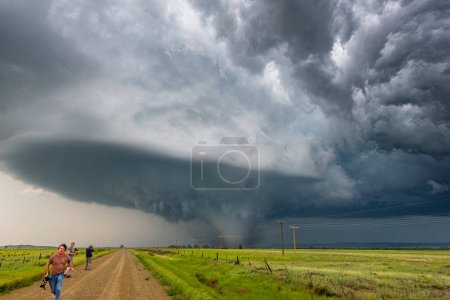 Téléchargez les photos : Les chasseurs de tempêtes fuient une énorme tornade le long d'une route poussiéreuse - en image libre de droit