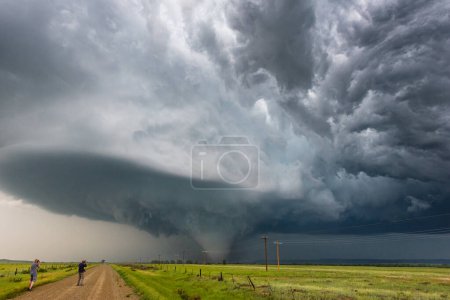 Sturmjäger fotografieren einen Tornado unter einem spektakulären Superzellen-Sturm entlang einer Feldstraße in Montana