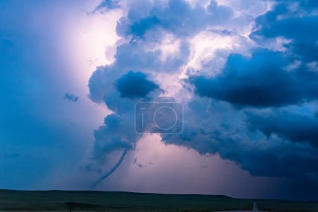 Tornado bajo una nube oscura iluminada por relámpagos