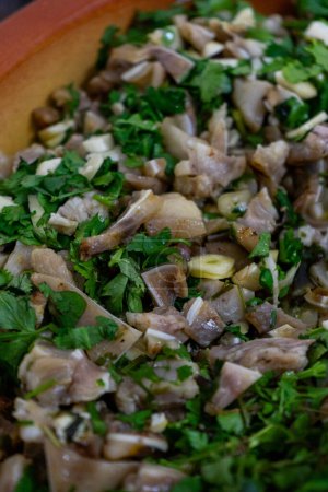 Nahaufnahme des traditionellen portugiesischen Gerichts "Orelha de Porco de Coentrada". Das Bild zeigt zarte Schweineohrscheiben, garniert mit frischem Koriander und Knoblauch