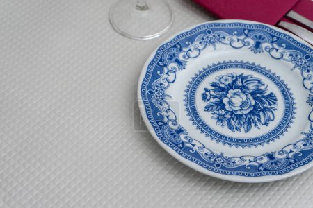 A white plate with blue patterns sits on a table in a traditional restaurant. The intricate design on the plate adds a touch of elegance to the simple yet inviting dining setting.