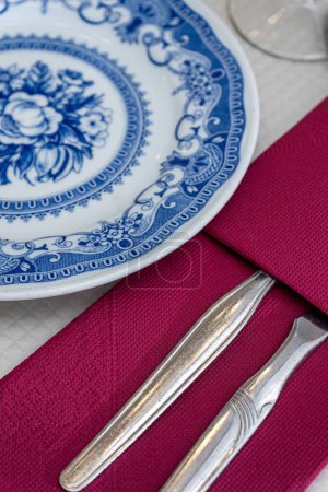 In eine lila Serviette gewickeltes Besteck sitzt neben einem Keramikteller auf einem Holztisch in einem traditionellen Restaurant in Alentejo. Die Einrichtung schafft eine warme und einladende Atmosphäre.
