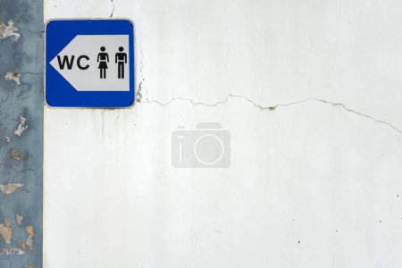 A simple blue and white sign indicating the location of public restrooms in a city. It shows clear, bold lettering with a classic symbol, such as a male and female icon, pointing in a direction.