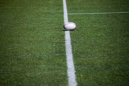 Rugby-Ball auf saftig grünem Feld, einsatzbereit. Dynamische Komposition fängt die Essenz des Spiels ein.