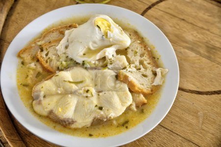 Téléchargez les photos : Cuisine portugaise traditionnelle : Sopa de Cao, une soupe de poisson robuste avec des aiguillats, des tomates, des oignons et de la coriandre. Un délice côtier du Portugal. - en image libre de droit