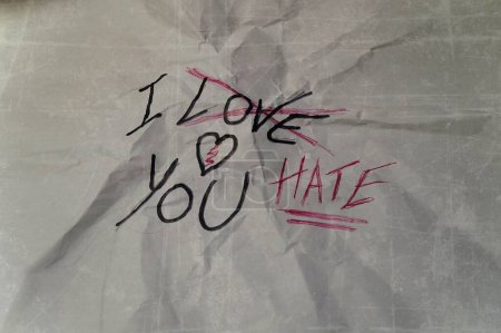 zerknülltes Blatt Papier mit der Aufschrift "Ich liebe dich", durchgestrichen und durch "Ich hasse dich" ersetzt, Konzept der schmalen Linie, die Liebe von Hass trennt, in Beziehungen