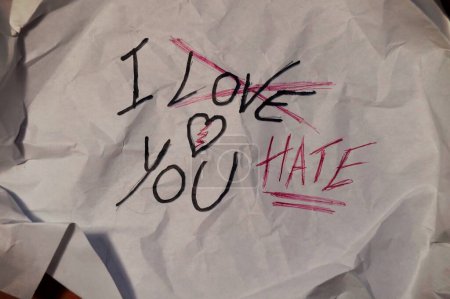 hoja de papel arrugado, con la escritura, "te amo", tachado y reemplazado por "te odio", concepto de la delgada línea que separa el amor del odio, en las relaciones