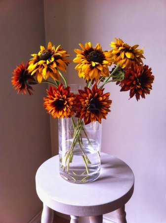 Bouquet of bright Helenium  flowers (Helenium in a glass vase on a stool