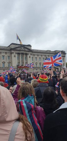 Photo for The royal family stands on a balcony and greets a crowd of cheering people after their coronation at Buckingham Palace - Royalty Free Image