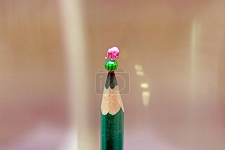 Obra de joyería de un maestro en la punta de un lápiz verde. Elefante y sandía. Foto de alta calidad