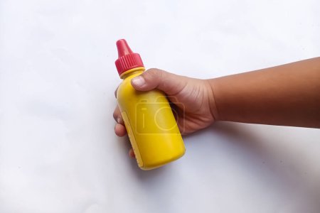 main de la personne asiatique tenant une bouteille en plastique jaune contenant du liquide antiseptique