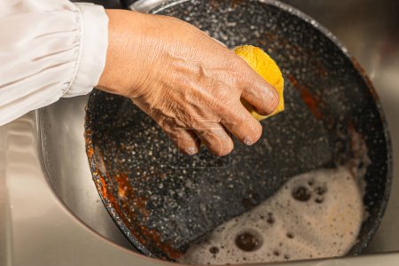 Téléchargez les photos : Femme lavage sale poêle à frire avec sauce dans l'évier, vue sur le dessus. - en image libre de droit