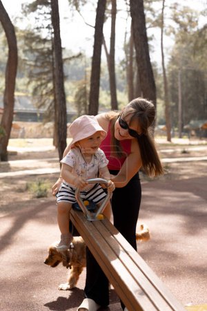 feliz madre juega y empuja a su hijo en un columpio en el parque en un día de aguas termales. Foto de alta calidad 