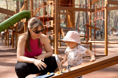 Photo for Happy mother plays and pushes her child on a swing in the park on a hot spring day. High quality photo - Royalty Free Image