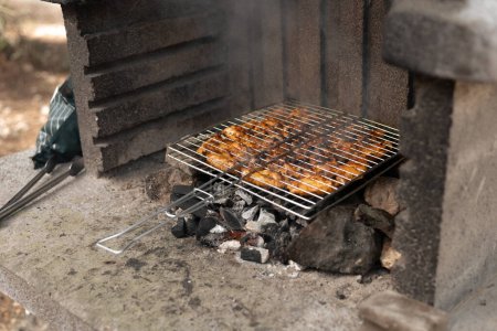 Photo for Photo of a barbecue for cooking shish kebab with a grid of meat in a picnic park in forest, hot spring day. High quality photo - Royalty Free Image