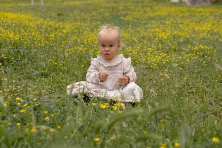 Photo for Cute baby girl in a beige dress in yellow flowers - Royalty Free Image