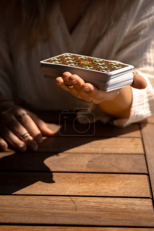 Woman in a light outfit reads Tarot cards on a table in a cafe, close-up view